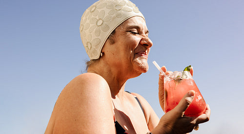 Mature woman enjoying a tiki cocktail in the summer