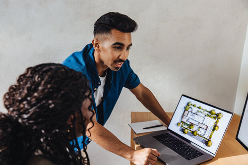 Young male architect presenting a project to a colleague with architectural blueprint