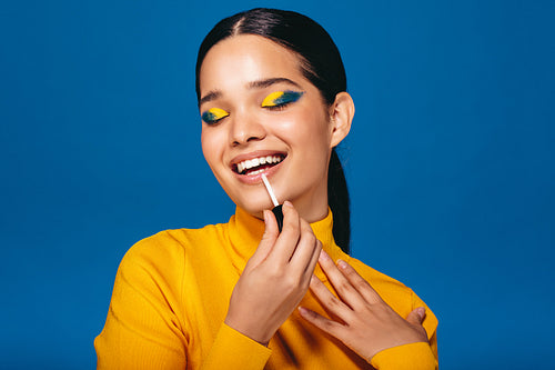 Glamour girl: Generation Z woman applying lip gloss in a studio