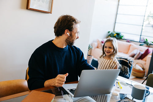 Man with daughter working on laptop at home