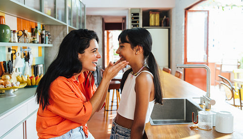 Smiling mother and daughter spending quality time in the modern kitchen
