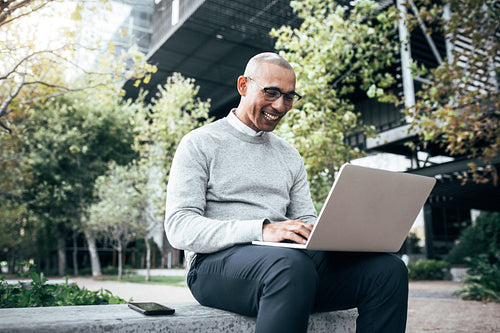 Businessman working on laptop computer sitting outdoors