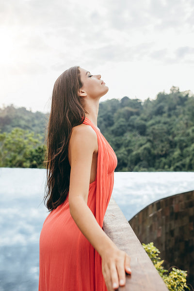 Beautiful young female standing at poolside railing