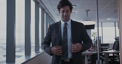 Young businessman buttoning jacket