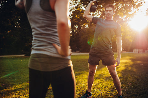 Fit young man exercising in park with trainer