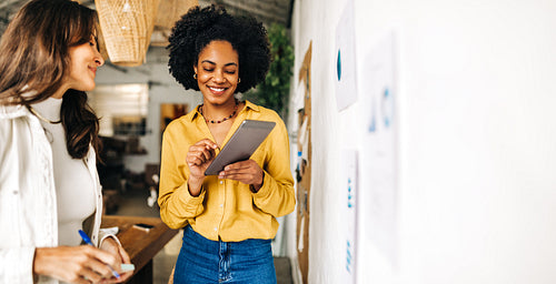 Business women using a tablet together in a brainstorming meeting