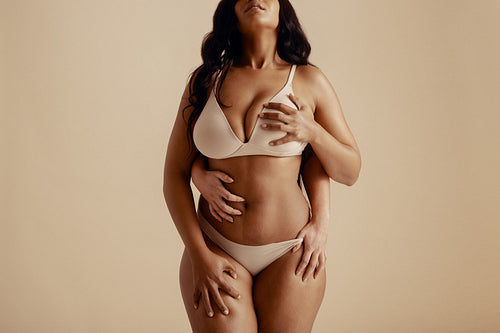 Intimate sensuality: A young woman embracing pleasure and fantasy in studio setting