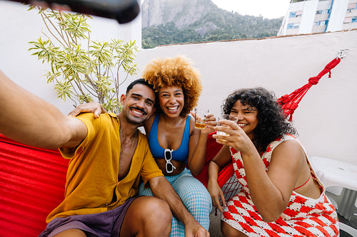 Friends taking selfie with drinks on rooftop in Rio de Janeiro