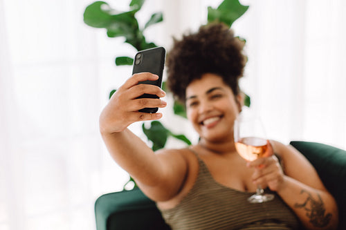 Woman with wine taking selfie on cell phone