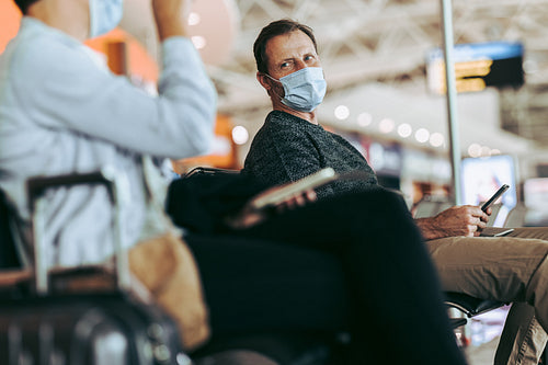 Male traveler sitting at airport terminal in pandemic