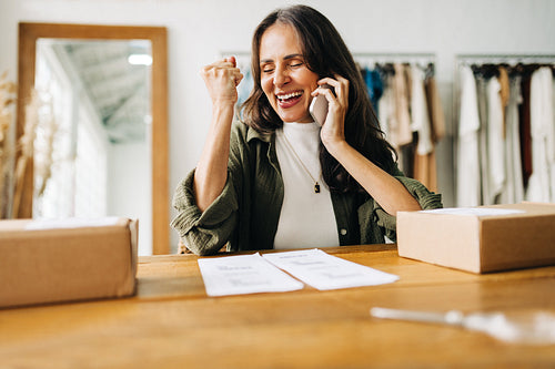 Ecommerce success: Business woman celebrates on a phone call