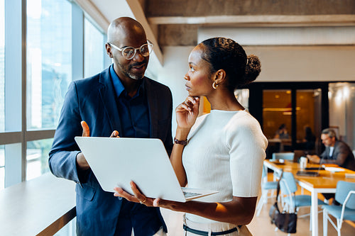 Colleagues discussing a project using a laptop in an office setting