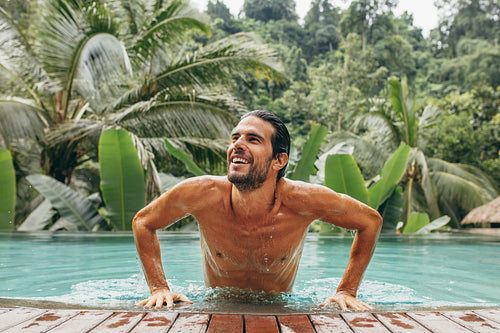 Happy young man in luxury holiday resort pool