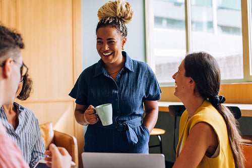 Smiling colleagues sharing a conversation during a casual workspace moment together