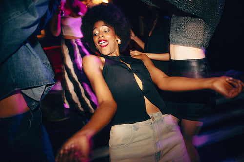 Excited woman dancing at a lively party with friends and vibrant lights