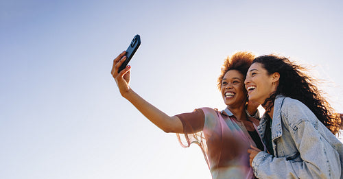 Female friends in their 20s taking a selfie outdoors on a summer's day