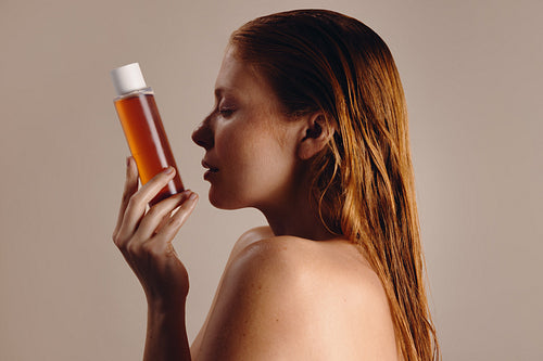 Woman holding amber bottle skincare product in profile