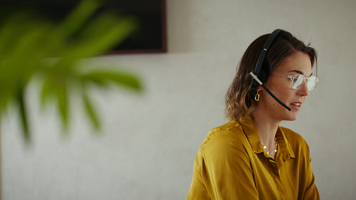 Business professional woman with a headset using her laptop in the office