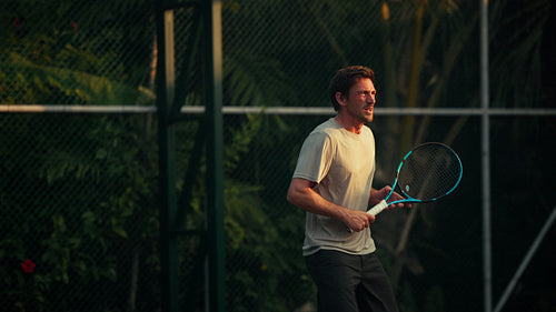 Man playing active tennis on an outdoor court, striking a powerful forehand shot