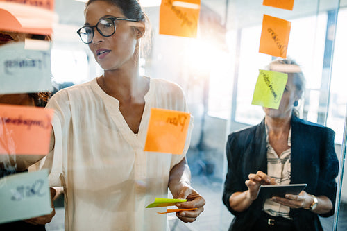 Creative professionals looking over a post it note wall and discussing