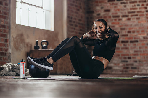Smiling female in the gym doing sit-up