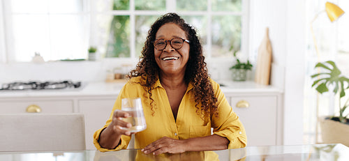 Keeping hydrated in her golden years: Senior woman drinking water at home