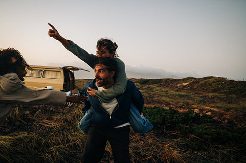 Friends share a playful piggyback moment during a sunset roadside adventure