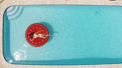 Woman relaxing on floating mattress in pool