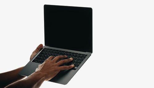 Male hands using a laptop with a black screen against a white background