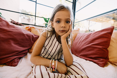 Child on sofa looking thoughtful with bracelets