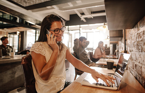 Happy businesswoman at office talking on mobile phone