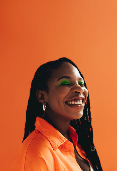 Cheerful woman with makeup and face piercings smiling in a studio