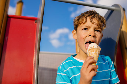 Boy eating an ice cream sitting on a slide