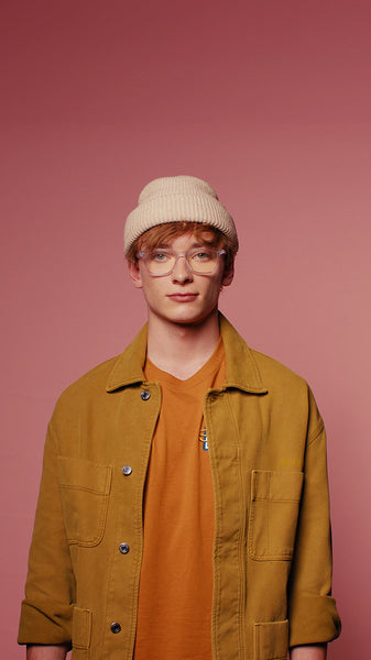 Young man in glasses and beanie poses for vertical medium shot