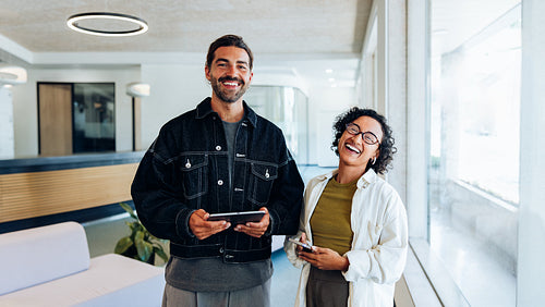 Two friends stand in a friendly office lobby