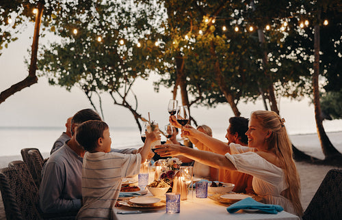 Family enjoying dinner at a beachside vacation with a toast