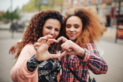 Friends making heart shape with fingers