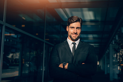 Smiling young businessman standing with his arms crossed