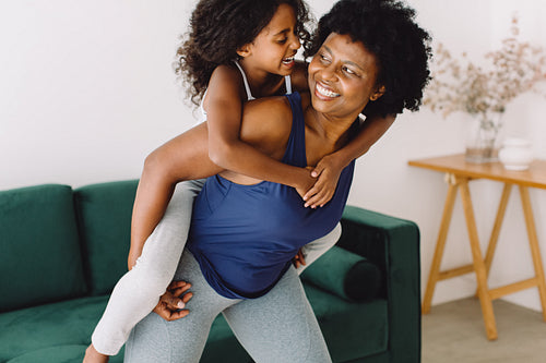 Mature woman in fitness wear carrying girl on her back