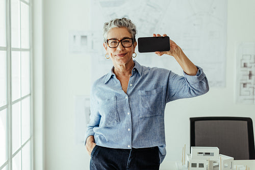 Technology in architecture: Professional architect showing her smartphone in an office