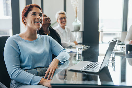 Happy business woman listening to a business presentation in a boardroom