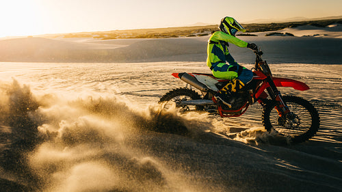 Biker accelerating on sand dunes