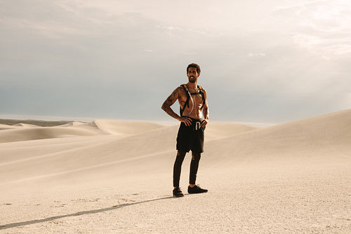 Fitness man standing on sand dune during workout