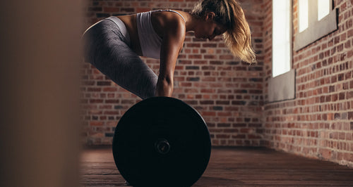 Muscular woman in gym doing heavy weight exercises
