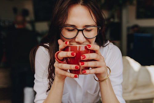Woman smelling aroma of coffee at cafe