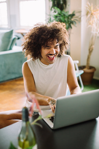 Happy young man updating his personal blog at home
