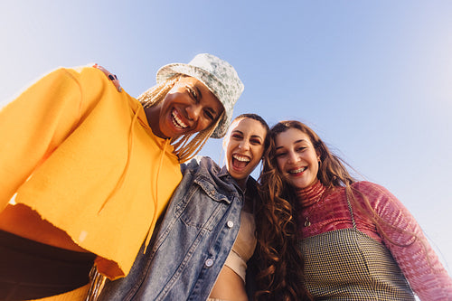 Low angle view of three friends smiling cheerfully