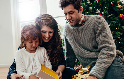 Little girl opening her Christmas present.
