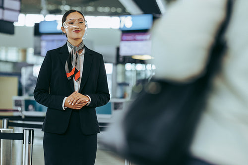 Flight attendant with glass shield at airport