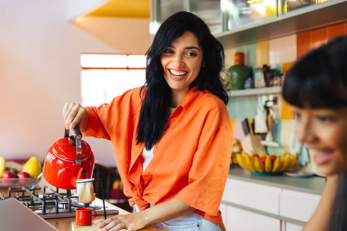 Woman preparing coffee at home while enjoying a cheerful morning together